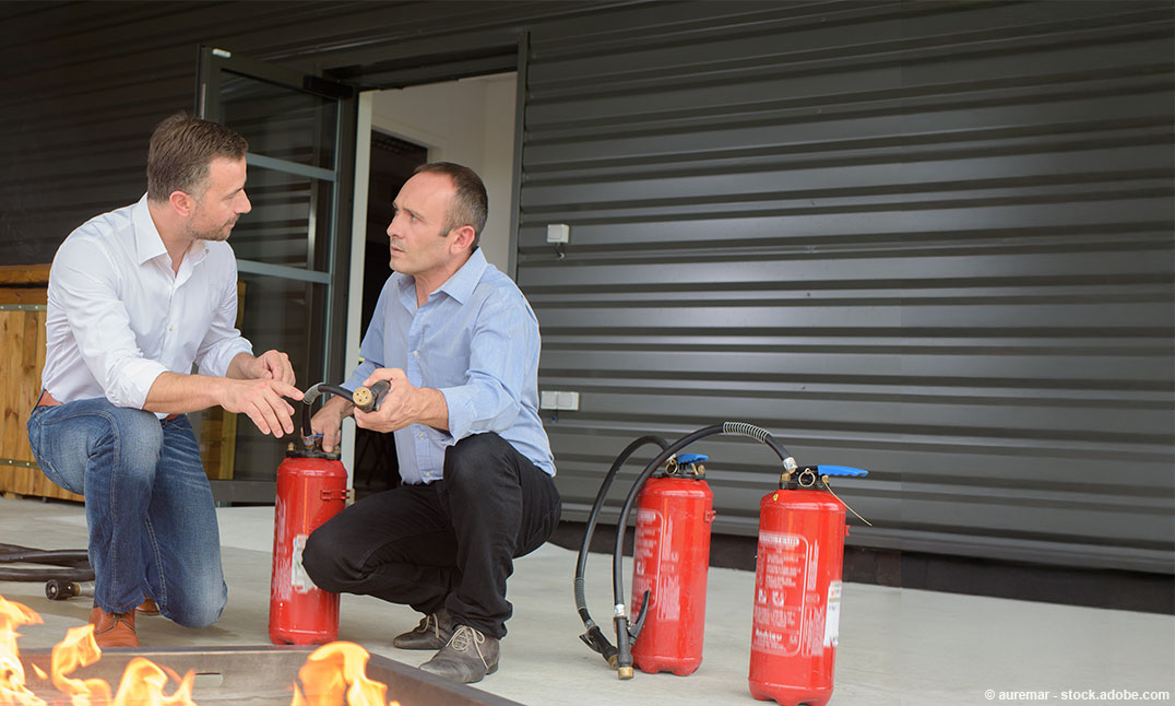 Zwei Männer üben das Löschen eines Feuers mit einem Feuerlöscher