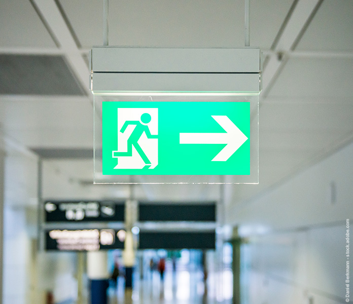 Beleuchtetes Notausgang-Hinweisschild in öffentlichem Durchgang