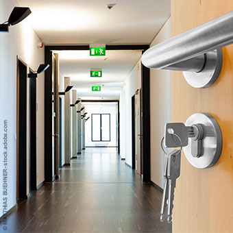 Ansicht eines Büroflurs mit drei beleuchteten Notausgang-Schildern an der Decke